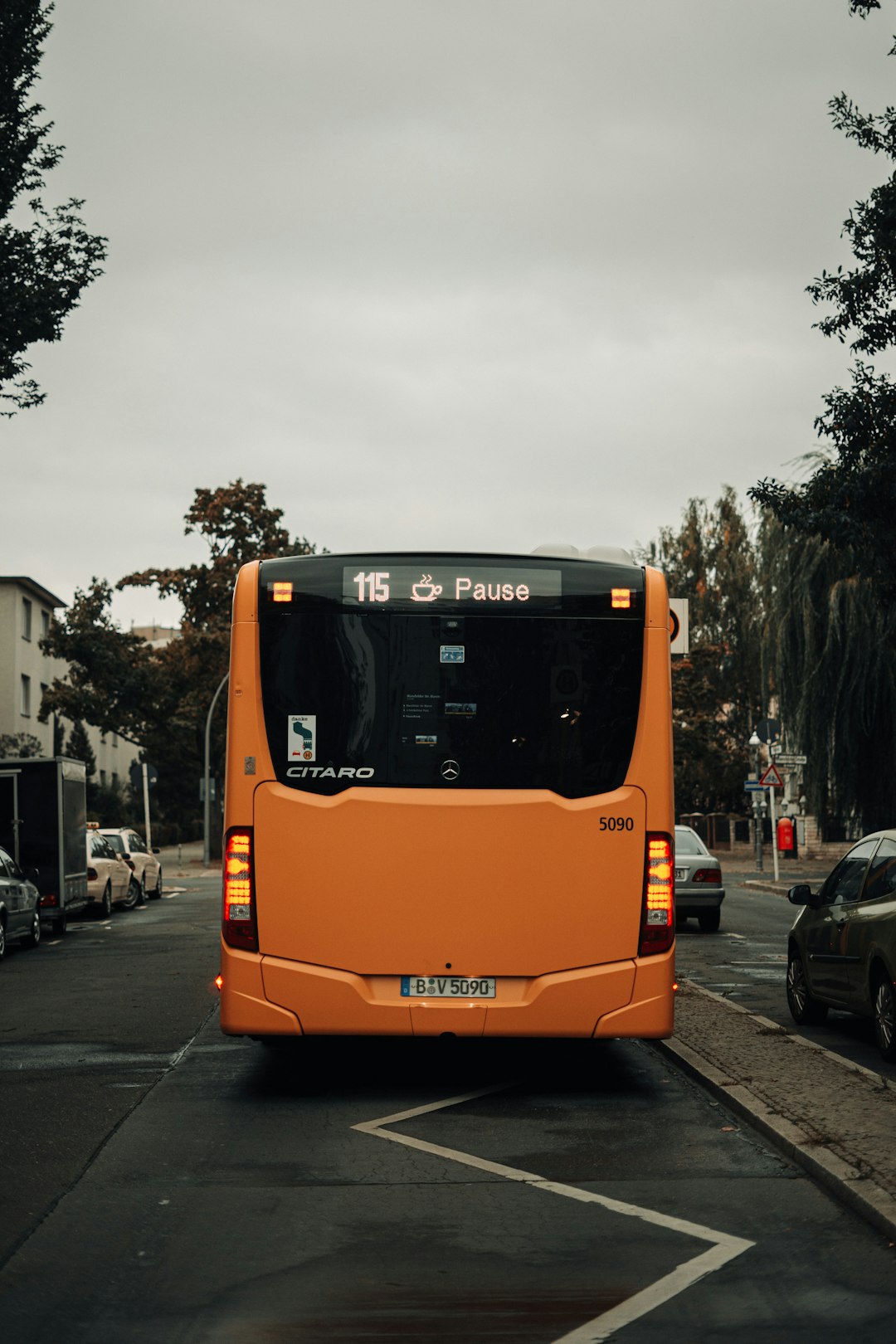Services a-large-orange-bus-driving-down-a-street-ixmidw350k0
