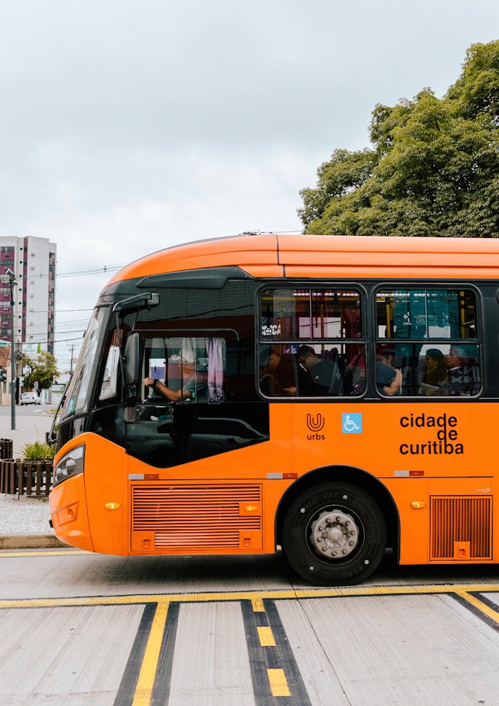 Orange Curitiba public bus on urban street, showcasing modern transportation in the city.